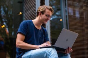 A smiling man using a laptop.