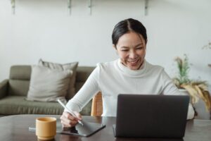 A smiling person working on a laptop.